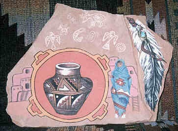 Irregular hexagonal flat sandstone painted 
with Native Mexican motives in Native style in pastel colors. 
Dominating from central left is a round bordered circle with 
diagonal markings of the Four Directions. In it a painting of 
a Mexican Native Jug, with zig-zag and other decorative motives. 
Left of the mandala four parts of a rising Pueblo with a ladder 
leading to the entries. Right of the mandala a woman stands in 
front of a Pueblo with a ladder and steep stairway. All but her 
face and white moccasins are wrapped in a beautifully decorated 
light-blue blanket.  Above the mandala six white archaic Animal 
Spirit symbols - Eagle, Wolf, Buffalo, Cariboo, Whale and Hawk – 
and two round dotted motives.  
To the right of this area a lower triangular level. One tattered 
Eagle feather fills the space. Its tip points downwards, fitting 
snug into the natural form of the stone. At the top a leather 
string wraps around the feather’s hollow shaft. An inlaid 
turquoise appears threaded onto the leather string. 
The stone leans against a handwoven carped showing similar 
motives and colors as the jug in the mandala.